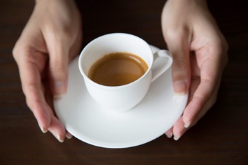 Hands of man holding entwine cup of coffee heart-shaped.