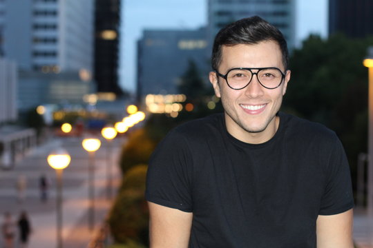 Cute ethnic male smiling in the city with copy space