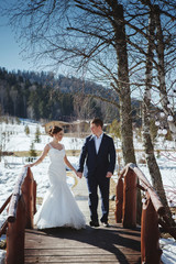 Winter wedding outdoors on snow background. Bride and groom are standing and hugging.
