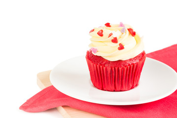Red Velvet Cup Cake topped with red, purple, pink heart shaped icing isolated on white background over wood board & red napkin for special holiday celebration, Valentines day or Christmas occasions