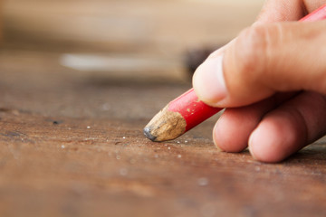 Carpenter drafting furniture by using pencil drawing to plank wood