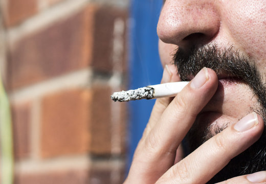 Whie caucasion man with beard smokin a cigarette