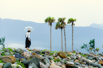 Asian lady with umbrella walking on the rocky beach of hualien, Taiwan