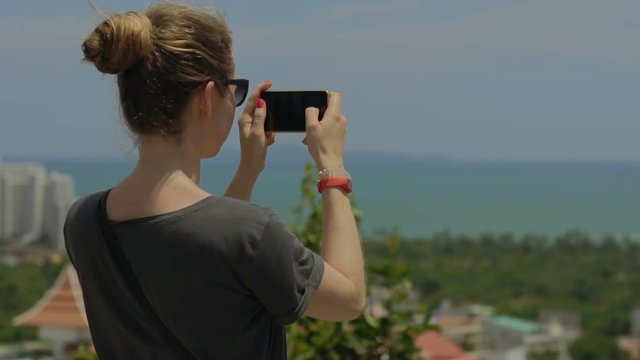 Tourist taking travel picture with phone during summer holidays. Unrecognizable female young adult enjoying in Asia.