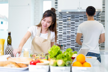 Asian couple cooking for food and salad for romantic diner in kitchen room in the home