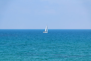 White sailboat floating on a calm sea.