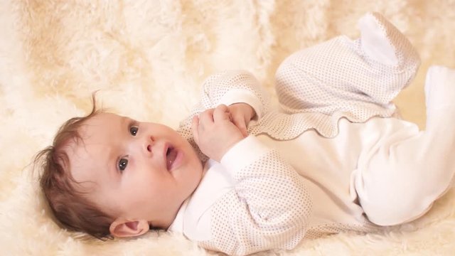 Small Baby In Body Lies On His Back, Playing With His Hands, Legs And Talking.