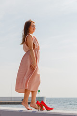 Woman wearing long light pink dress on jetty