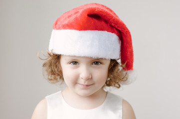 funny little curly blonde girl in a Santa hat