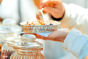 Close-up of woman hand preparing a plate with food in street setting