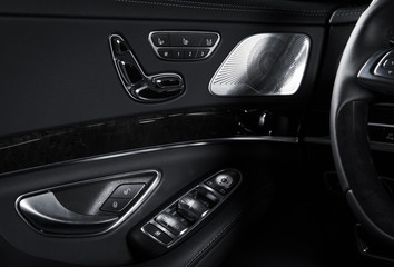 Fototapeta na wymiar Door handle with Power seat control buttons of a luxury passenger car. Black leather interior of the luxury modern car. Modern car interior details