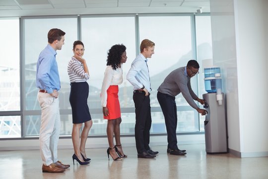 Business people standing by water cooler at office