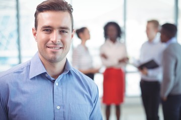 Businessman smiling with colleagues standing in background