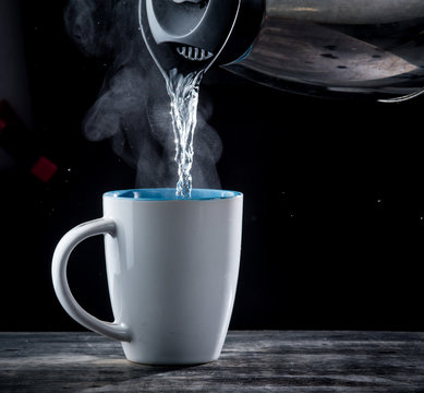 Pouring hot water into into a cup on a black background