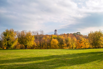 Autumn trees with a meadow and a church on the hill