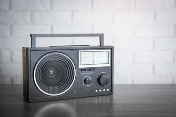 Vintage radio on wood table over white brick wallpaper background