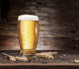 Frosted glass of beer on the wooden table.