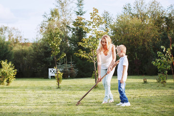 The boy and his mother to rake a beautiful lawn in your garden
