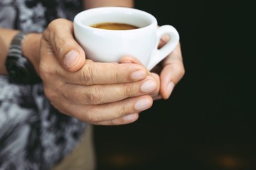 Hands of man holding entwine cup of coffee heart-shaped.