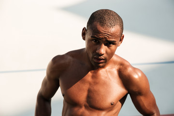 Close-up portrait of a sweaty handsome african sports man, resting after workout on stadium