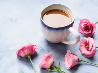 Mug of coffee and pink flowers on blue background. Festive mother valentine day greeting card