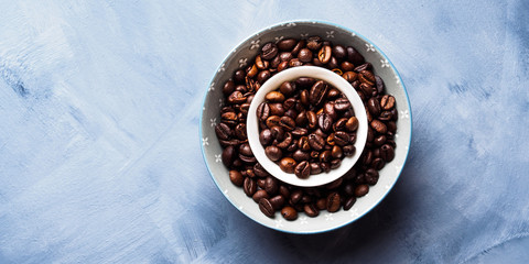 Whole Coffee beans in bowl on blue background