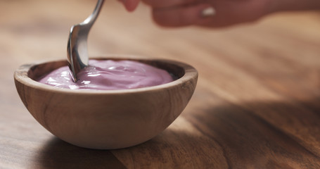 young female hand eating blueberry yogurt with spoon