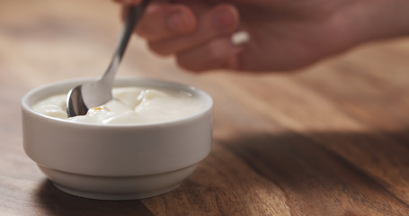 young female hand eating peach yogurt with spoon