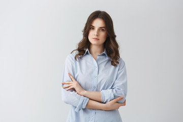 Portrait of beautiful stunning girl with dark hair crossing hands, looking in camera with relaxed and serious expression posing for university graduation album.