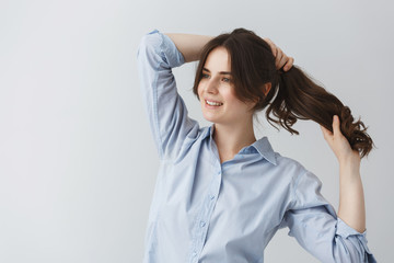 Fototapeta premium Young good-looking caucasian girl making hairstyle, getting ready for going out early in the morning with happy face expression.