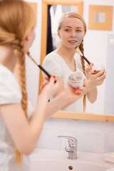 Woman applying with brush clay mud mask to her face