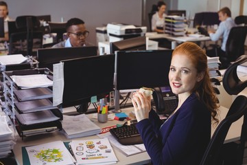 Portrait of businesswoman having snack while colleagues working