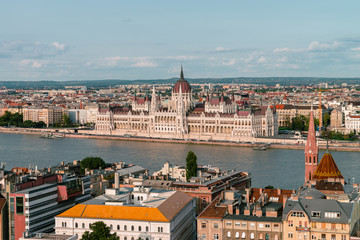 Obraz premium Panoramic view on the Hungarian Parliament Building on the bank of the Danube in Budapest. Sunny evening with clouds