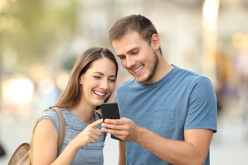 Happy couple using a smart phone on the street