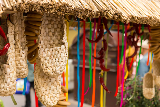 Straw shoes as a souvenir hanging from the counter next to the bagels and multi-colored ribbons at the fair