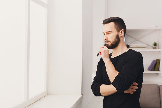 Young man vaping e-cigarette on white