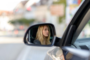 Fototapeta na wymiar Reflection of blonde woman in car wing mirror