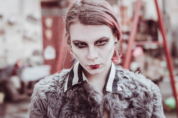 Bloody young woman at the yard with creepy toys. halloween make up