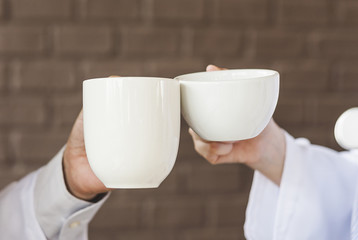 hands with cups of hot coffee or hot tea. Clink glasses with two cups of coffee