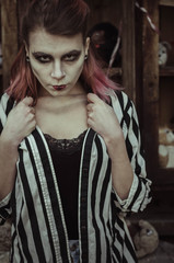 Bloody young woman at the yard with creepy toys. halloween make up