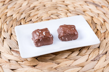 Two salted chocolate caramels on a woven mat