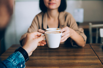 Man proposes gives coffee in white little cup to his girlfriend or partner, they are in love and are on romantic date in downtown stylish cafe or restaurant, drink artisan speciality