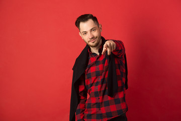 Fototapeta premium portrait of a stylish young guy in a checked shirt on a red background in a good mood and smiling