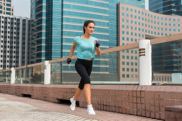 Attractive sporty young woman running on pavement