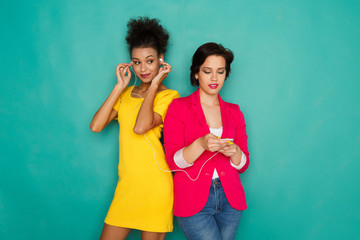 Happy female friends listen to music at studio background