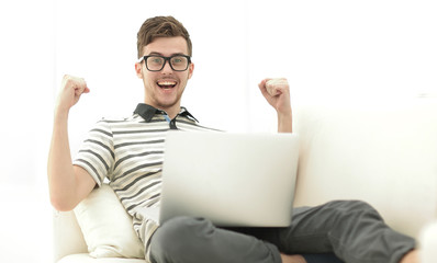 happy man with laptop sitting on the couch