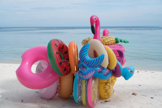 Bunch of many colorful inflatable toys isolated on the sandy beach over blue sea and sky background