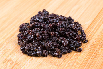 Black organic zante currants on a wood background