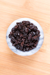 Black organic zante currants on a wood background