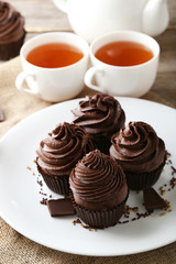 Chocolate cupcakes in plate with cup of tea on wooden table